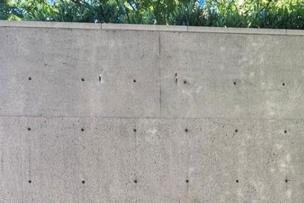 The same concrete wall after cleaning, uniform light grey with the form lines visible