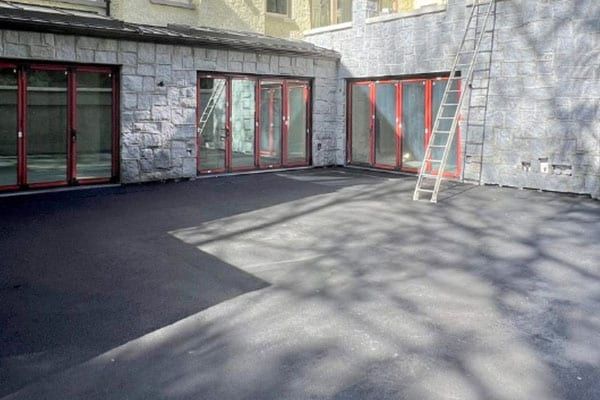 The same courtyard after pressure washing, asphalt restored to an even dark finish