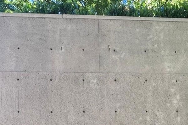 The same concrete wall after cleaning, uniform light grey with the form lines visible
