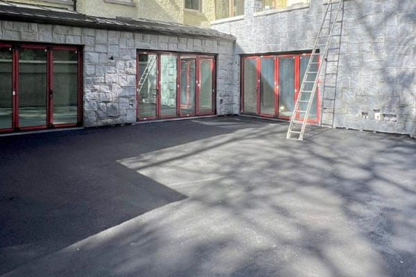 The same courtyard after pressure washing, asphalt restored to an even dark finish